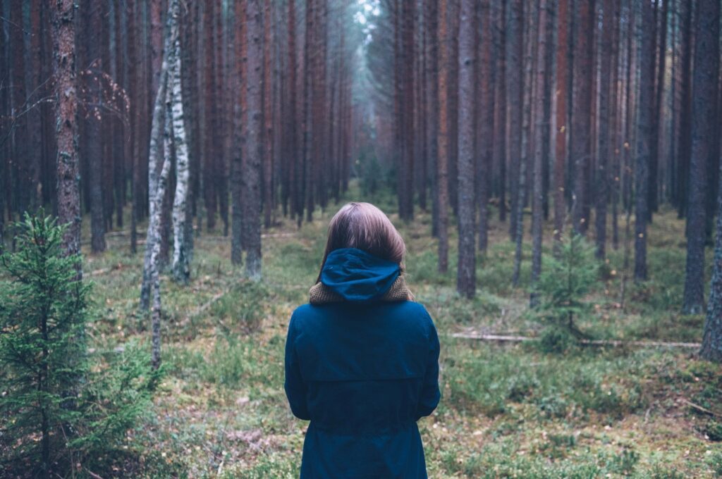 Woman wearing a blue coat in a forest