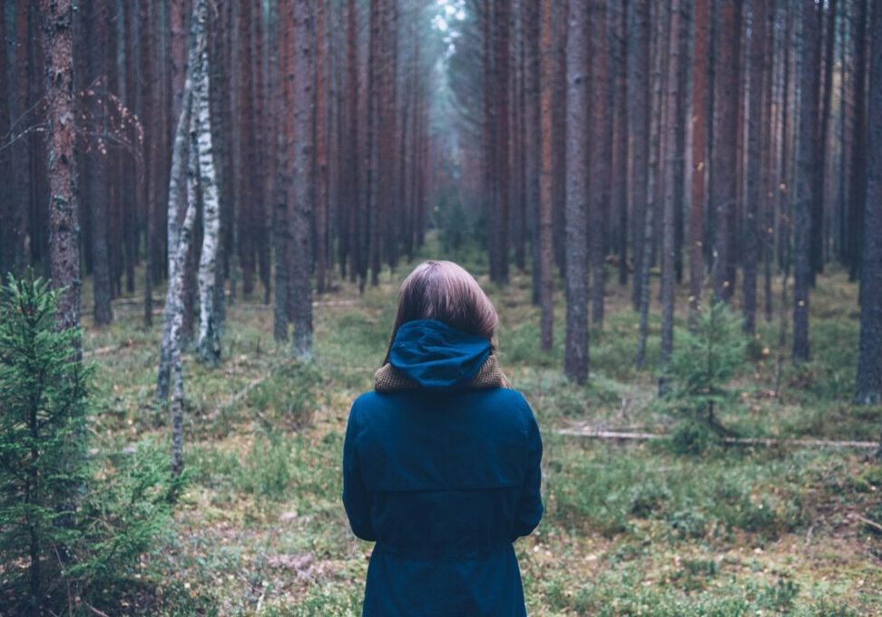 Woman wearing a blue coat in a forest